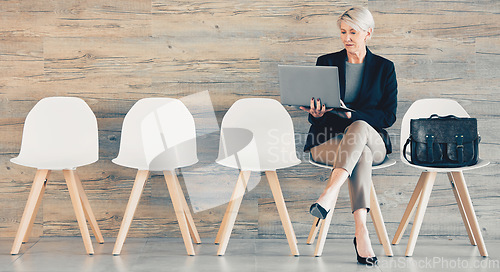 Image of Every time you conquer one it makes you stronger. a mature businesswoman using a laptop while waiting in line at an office.