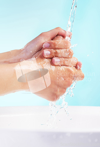 Image of May your day be as flawless as your skin. an unrecognizable woman washing her hands against a blue background.