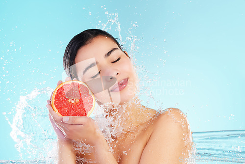 Image of It’s a SKIN-vestment. Studio portrait of an attractive young woman posing with a grapefruit in her hand against a blue background.