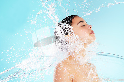 Image of Real women take care of their skin. a beautiful young woman being splashed with water against a blue background.