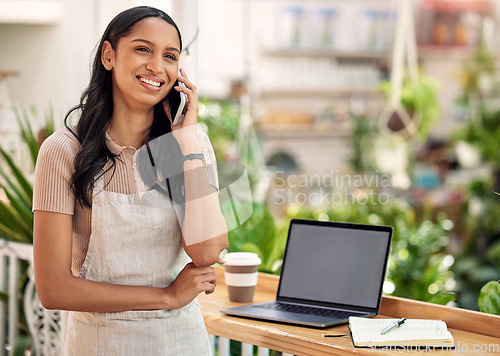 Image of Never gave up, never gave in. a young florist using her smartphone to make a call while using a laptop.