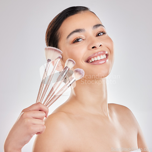 Image of Time to paint my face. a young woman applying makeup to her face against a grey background.