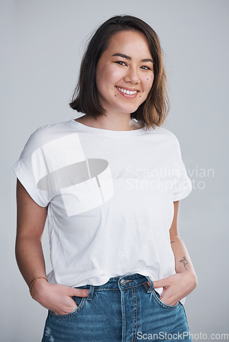 Image of Carry yourself with a smile. a beautiful young woman posing against a grey background.