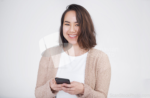 Image of What should I text back. a beautiful young woman posing against a grey background.