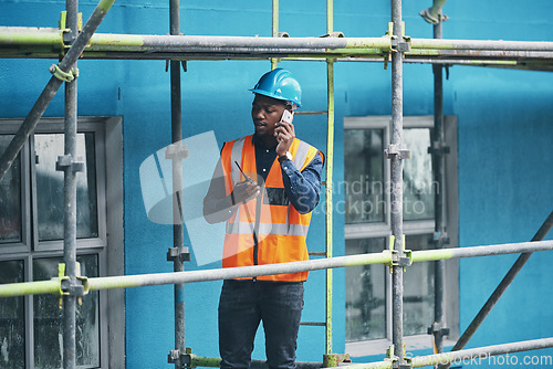 Image of Monitoring the flow of a new build. a young man talking on a cellphone while working at a construction site.