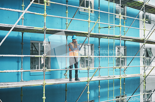 Image of Engineers simple love solving problems. a young man talking on a cellphone while working at a construction site.