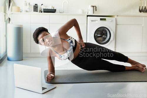 Image of Planking creates definition in your abs. a young woman using a laptop while exercising at home.