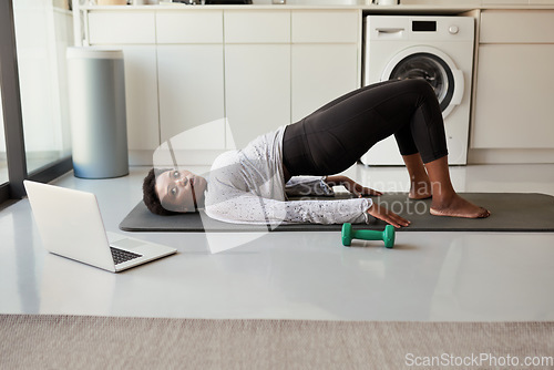 Image of Staying active is one of the best things for your health. a young woman using a laptop while exercising at home.