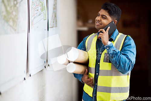 Image of This is a big project, Ill need everyone on it. a young engineer talking on his cellphone while reading something on a wall.