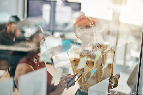 Image of Planning every step to success in detail. two businesswomen brainstorming with notes on a glass wall in an office.