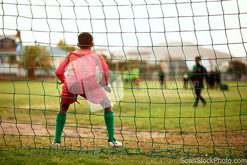 Image of Will he be able to block the shot. Rearview shot of a young boy standing as the goalkeeper while playing soccer on a sports field.