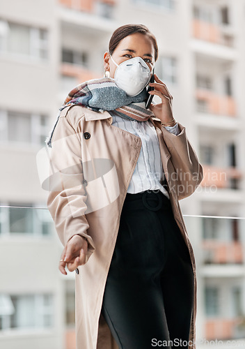 Image of Weve adjusted well to the new norm. a young woman wearing a mask while talking on the phone on the balcony at home.