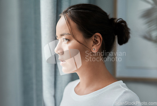 Image of Im feeling a bit down today. a beautiful woman looking out the window at home.