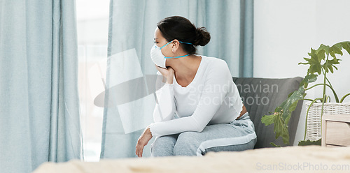 Image of Theres so much I want to do when its all over. a young woman wearing a mask while looking out a window at home.