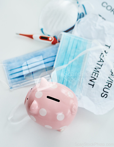 Image of This pandemic has everyone digging into their savings. a piggybank and coronavirus props against a white background.