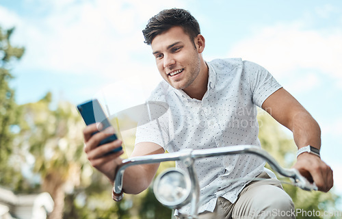 Image of The more mobile the more he makes things happen. a young businessman using a smartphone while riding his bicycle in the city.