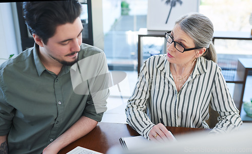 Image of Going over some new terms for their business. two businesspeople going through paperwork together in an office.