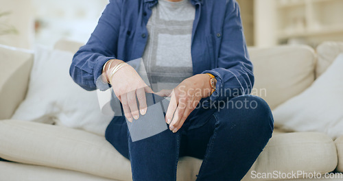 Image of Home, injury and senior woman with knee pain, massage and inflammation in a living room. Pensioner, old person and elderly lady on a couch, accident or emergency with bruise, broken or muscle tension