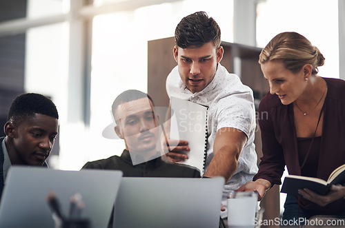 Image of Diligent work leads to the best results. a group of businesspeople working together on a laptop in an office.
