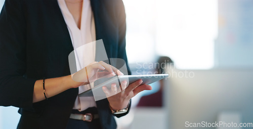 Image of Doing research off the record. an unrecognizable businesswoman browsing on her digital tablet inside of the office during the day.