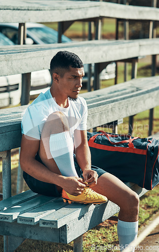 Image of Getting ready to give his best on the field. a rugby player tying his shoelaces while sitting on a bench.