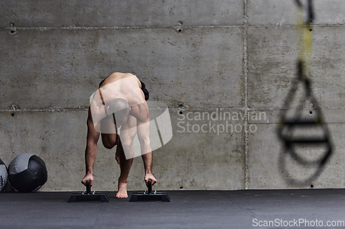 Image of A muscular man in a handstand position, showcasing his exceptional balance and body control while performing a variety of exercises to enhance his overall body stability and strength in a modern gym