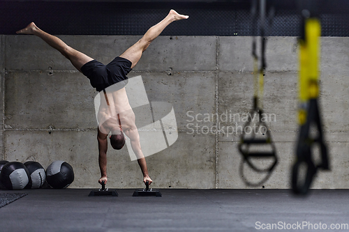 Image of A muscular man in a handstand position, showcasing his exceptional balance and body control while performing a variety of exercises to enhance his overall body stability and strength in a modern gym