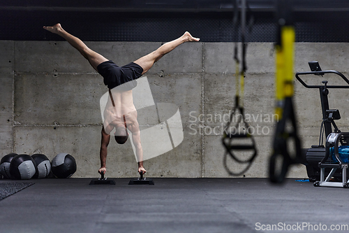 Image of A muscular man in a handstand position, showcasing his exceptional balance and body control while performing a variety of exercises to enhance his overall body stability and strength in a modern gym