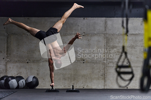 Image of A muscular man in a handstand position, showcasing his exceptional balance and body control while performing a variety of exercises to enhance his overall body stability and strength in a modern gym