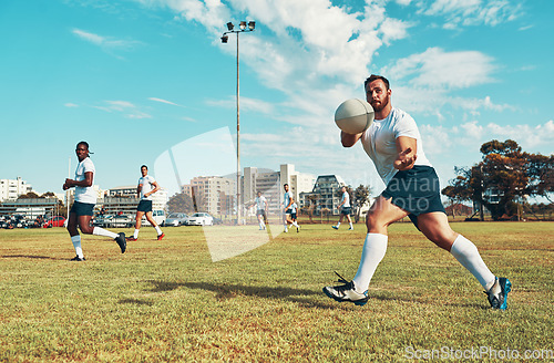 Image of He never misses a pass. young men playing a game of rugby on a field.