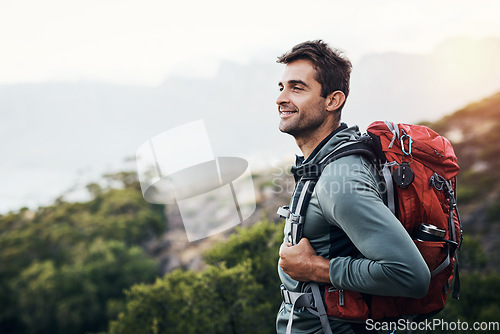 Image of I can see my house from here. a cheerful young man looking into the distance while going for a hike up a mountain.