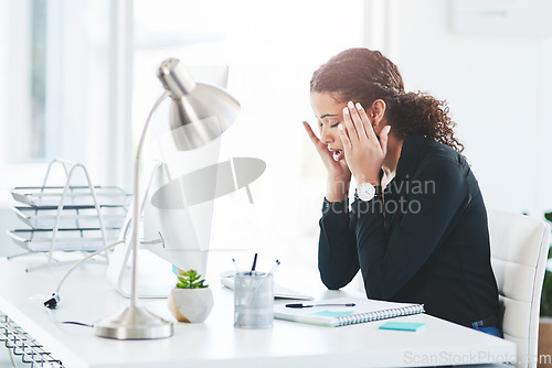 Image of This headache is really starting to pound me down. a young businesswoman looking stressed out while working in an office.