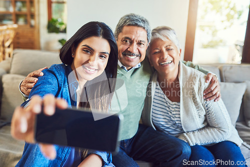 Image of Capturing every special moment. a cheerful senior couple and their daughter taking a selfie together while sitting on a couch at home.