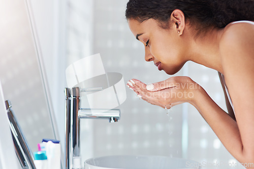 Image of Its time to feel refreshed. a young woman washing her face in the bathroom at home.