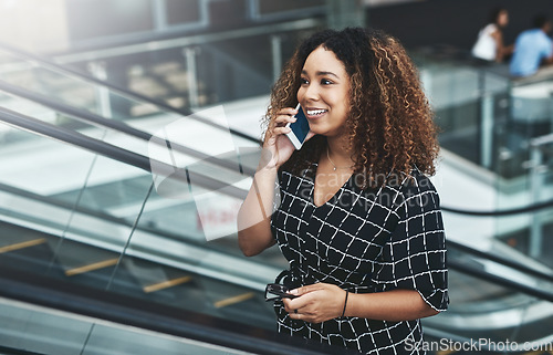 Image of Ill inform everyone of the good news right away. an attractive young businesswoman taking a phonecall while moving up an escalator in a modern workplace.