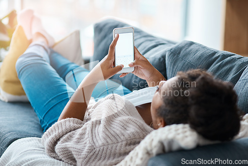 Image of Let me reply to a few texts. Full length shot of an unrecognizable woman using her smartphone while lying on the sofa.