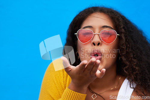 Image of This ones especially for you. Studio portrait of an attractive young woman blowing a kiss against a blue background.