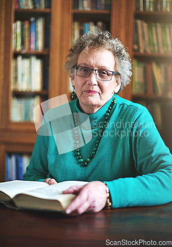 Image of Getting in a great read. Portrait of a senior woman sitting at a table reading.