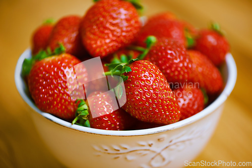 Image of Fresh from the garden. a bowl of strawberries on a wooden table.