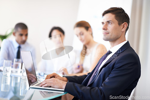 Image of Hes connected when you need him. Portrait of a content businessman using a laptop during a meeting.