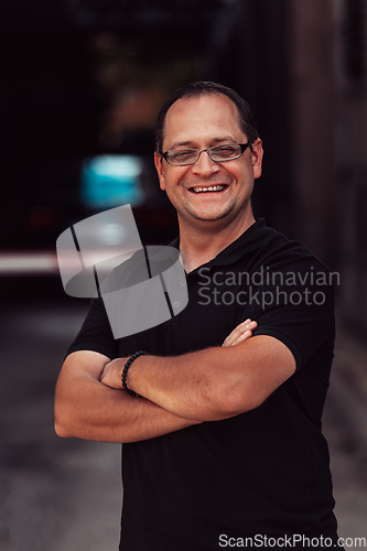 Image of A successful businessman with crossed arms, posing outdoors