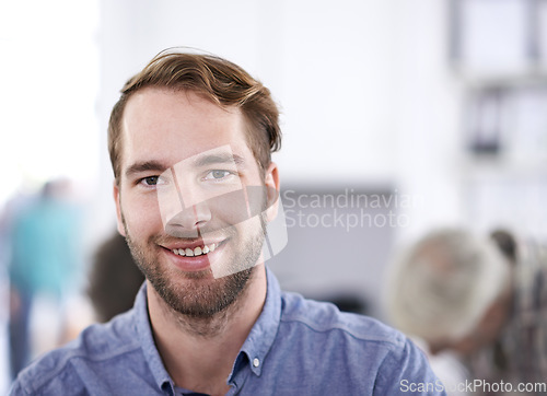 Image of My job actually makes me happy. Portrait of a handsome young businessman with his colleagues working in the background.