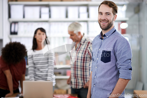 Image of This business is the perfect fit for me. Portrait of a handsome young businessman with his colleagues working in the background.