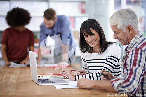 Image of You can sense the creativity in the air. Two mature designers working together in an office environment with their colleagues in the background.