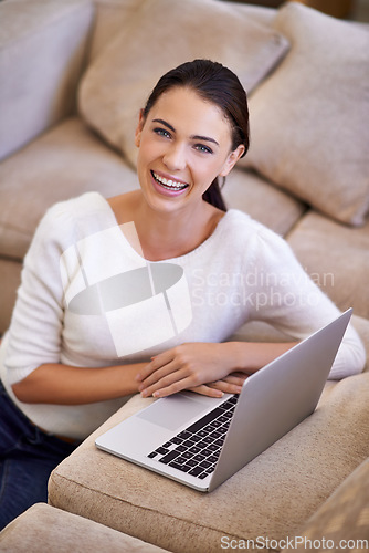 Image of Ive got everything I need right here. a young woman sitting in her living room using a laptop.