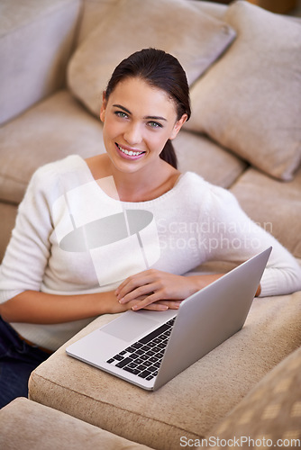 Image of Just updating my status as chilled. a young woman sitting in her living room using a laptop.