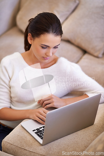 Image of Catching up with friends has never been easier. a young woman sitting in her living room using a laptop.
