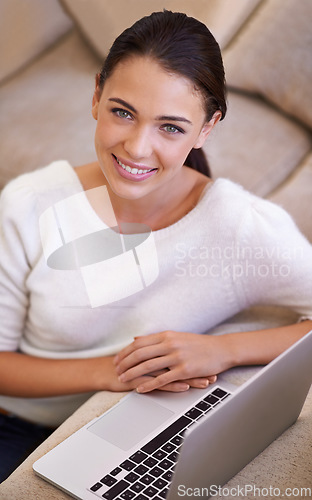 Image of Staying connected has never been easier. a young woman sitting in her living room using a laptop.