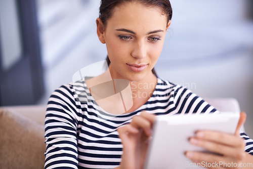 Image of What would I do without my tablet. A beautiful young woman using a tablet on her couch.