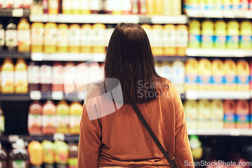 Image of So much choice so much pressure. a woman standing in front of the fridge in the supermarket.